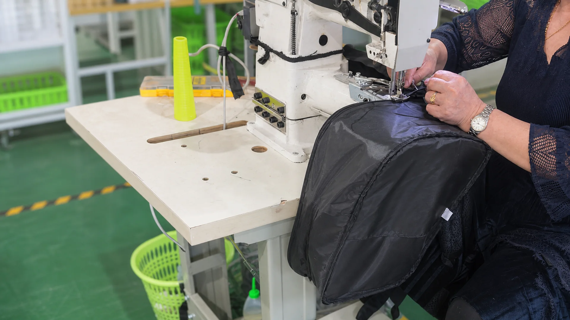 Worker sewing the structure of a black bag